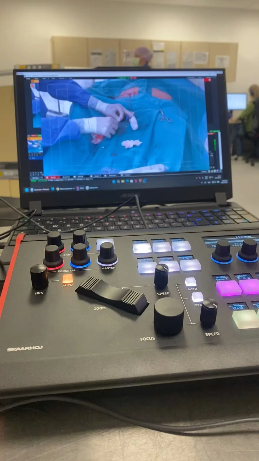 Laptop met het live beeld van een operatie, naast een Skaarhoj camerabediening op een regiewerkplek in de OK.