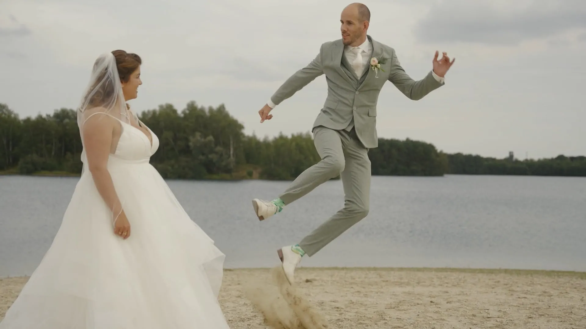 Bruidegom springt op het strand, spontaan moment uit een trouwvideo